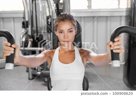 Gym workout Asian woman focused and motivated training on pec deck chest press fly machine. Fitness workout 100908620