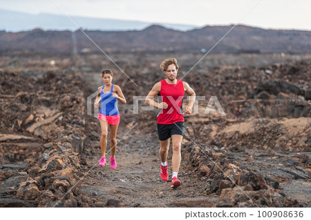 Run couple fit athletes training together running in volcanic trail field for marathon race. Male and female runners in sportswear clothes running shoes 100908636