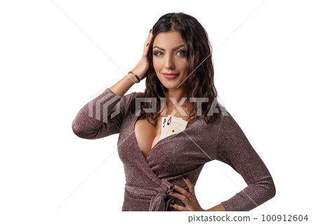 Brunette woman wearing in shiny brown dress. There are two playing cards on her breast. Isolated on white background. Casino, poker. Close-up. 100912604
