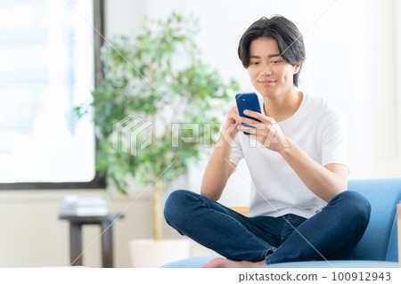 Male living room lifestyle smartphone living alone Male living room lifestyle smartphone living alone 100912943