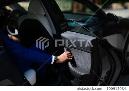 A man in a blue suit opens the car door. Close-up of a man's hand with an expensive watch. A man in a blue suit opens the car door. Close-up of a man's hand with an expensive watch. 100913084