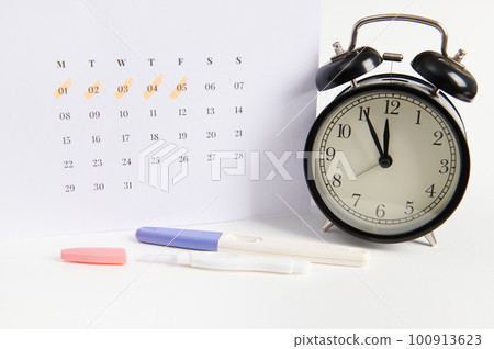 Positive inkjet pregnancy test, black retro alarm clock and white calendar with dates of the last menstruation marked. Women's health, ovulation, fertility, pregnancy planning and motherhood. Ad space Positive inkjet pregnancy test, black retro alarm clock and white calendar with dates of the last menstruation marked. Women's health, ovulation, fertility, pregnancy planning and motherhood. Ad space 100913623