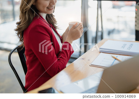 Portrait of a business woman talking on the computer and drinking coffee. 100914869