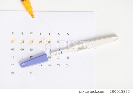 Top view of inkjet pregnancy test with a biochemical reaction between hCG and urine appearing in two bars above a white calendar with last menstrual dates marked. Rapid diagnosis of pregnancy at home Top view of inkjet pregnancy test with a biochemical reaction between hCG and urine appearing in two bars above a white calendar with last menstrual dates marked. Rapid diagnosis of pregnancy at home 100915853