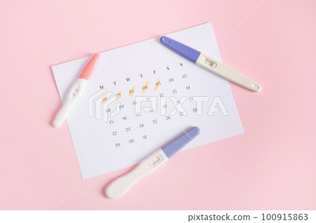 Flat lay Inkjet pregnancy test kits on a white calendar with marked dates in last menstruation, pink background. Calculation of ovulation day. Planning maternity. Gynecology and women's health concept Flat lay Inkjet pregnancy test kits on a white calendar with marked dates in last menstruation, pink background. Calculation of ovulation day. Planning maternity. Gynecology and women's health concept 100915863