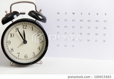 Close-up of a black retro alarm clock and white clean calendar, isolated over white color background with copy ad space. Busy work reminder, annual leave, project deadline or special event day concept Close-up of a black retro alarm clock and white clean calendar, isolated over white color background with copy ad space. Busy work reminder, annual leave, project deadline or special event day concept 100915883