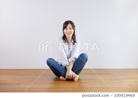 Smiling woman sitting cross-legged 100919469
