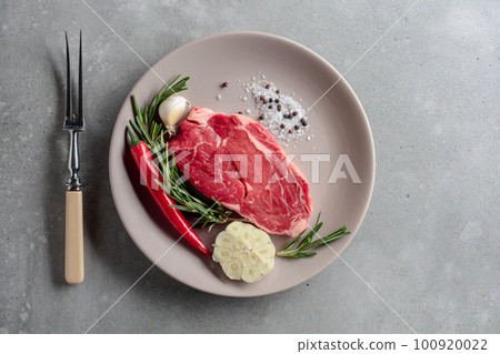 Raw beef steak with rosemary, garlic, salt, and pepper. Raw beef steak with rosemary, garlic, salt, and pepper. 100920022