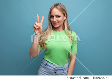 smart smiling girl in casual outfit showing two fingers on blue background smart smiling girl in casual outfit showing two fingers on blue background 100920258