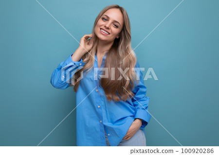 stylish casual blonde girl flirts and smiles on a blue isolated background stylish casual blonde girl flirts and smiles on a blue isolated background 100920286