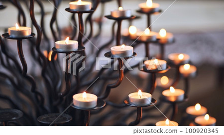 Candlestick holder with burning candles in a Catholic church. Candlestick holder with burning candles in a Catholic church. 100920345