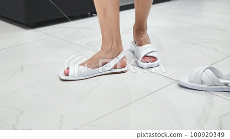 Girls trying on white summer sandals in the store. 100920349