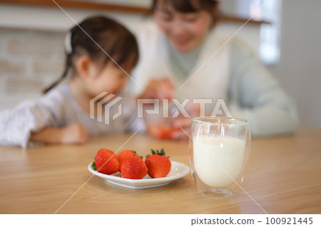 Parent and child making strawberry milk 100921445
