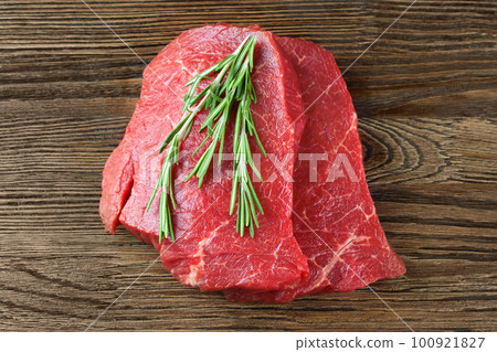 Fresh raw meat with rosemary on brown wooden background Fresh raw meat with rosemary on brown wooden background 100921827