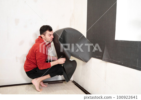 Repair the house with their own hands. The guy is ripping the old wallpaper off the wall Repair the house with their own hands. The guy is ripping the old wallpaper off the wall 100922641