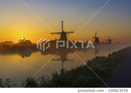 Traditional Dutch windmills with a colourful sky just before sunrise in Kinderdijk, The Netherlands 100923036