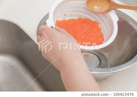 [製作醬油醃製三文魚子，用勺子將洗淨的生三文魚子與清酒混合] 100923476