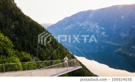 Young man standing on the viewing platform with drone controller view of Hallstatt lake, mountains Young man standing on the viewing platform with drone controller view of Hallstatt lake, mountains 100924036