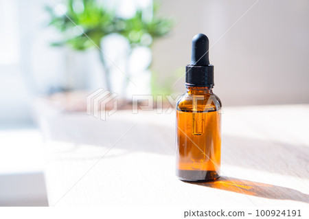 Brown amber glass serum oil dropper bottle and white towel on table mock-up, cosmetic container in real interior 100924191