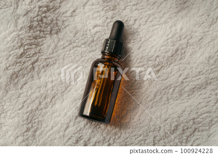 Amber glass serum oil dropper bottle laying on white towel mock-up, cosmetic container daylight shot Amber glass serum oil dropper bottle laying on white towel mock-up, cosmetic container daylight shot 100924228