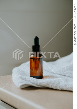 Amber glass serum oil dropper bottle and white towel on table mock-up, cosmetic container daylight shot 100924243