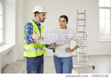 Young woman homeowner discussing design project of her new apartment with a foreman. Young woman homeowner discussing design project of her new apartment with a foreman. 100925189