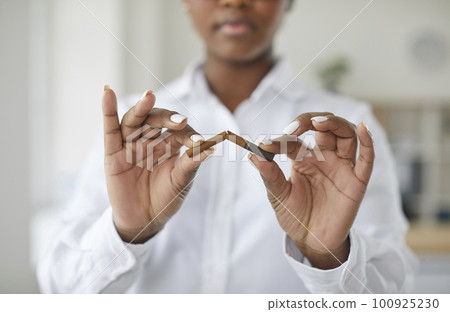 Beautiful African American girl breaking cigarette in half, focus on hands Beautiful African American girl breaking cigarette in half, focus on hands 100925230