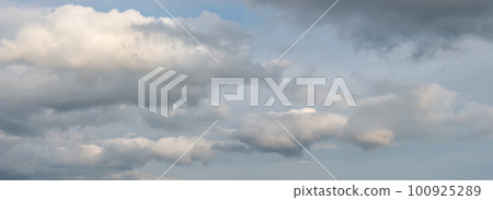 Panoramic view over soft blue sky with illuminated by sun rainy clouds as a background banner. 100925289