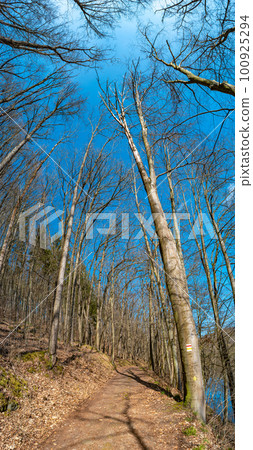 Hiking trail in magical deciduous and pine forest, rocky granite hills landscape at riverside of Zschopau river near Mittweida town, Saxony, Germany, at warm sunset and blue Spring sky. Hiking trail in magical deciduous and pine forest, rocky granite hills landscape at riverside of Zschopau river near Mittweida town, Saxony, Germany, at warm sunset and blue Spring sky. 100925294