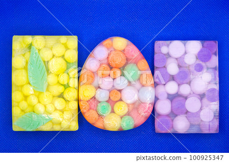 Three transparent pieces of soap with bright colored balls inside on a blue background Three transparent pieces of soap with bright colored balls inside on a blue background 100925347