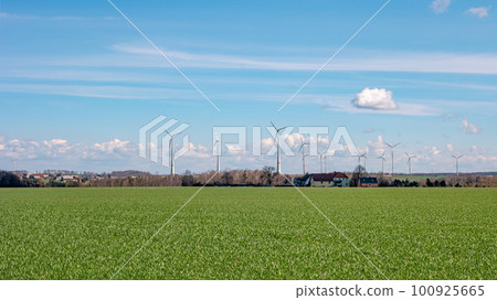 Panoramic view over beautiful farm landscape with early spring agriculture field, wind turbines to produce green energy near Mittweida, Germany, at blue sunny sky. 100925665