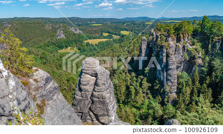 Panoramic over monumental Bastei sandstone pillars, rock formation and stacks surrounded by ancient forests at Kurort Rathen village in the national park Saxon Switzerland by Dresden, Saxony, Germany. 100926109