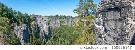 Panoramic view over monumental Bastei sandstone pillars and ancient bridge near Kurort Rathen village in the national park Saxon Switzerland by Dresden and Czechish border, Saxony, Germany. Panoramic view over monumental Bastei sandstone pillars and ancient bridge near Kurort Rathen village in the national park Saxon Switzerland by Dresden and Czechish border, Saxony, Germany. 100926147