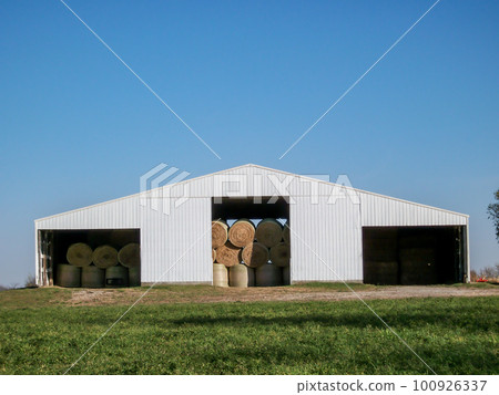 Granular old photo of round hay bales stacked in a sheet metal tin barn on a rural farm. Granular old photo of round hay bales stacked in a sheet metal tin barn on a rural farm. 100926337