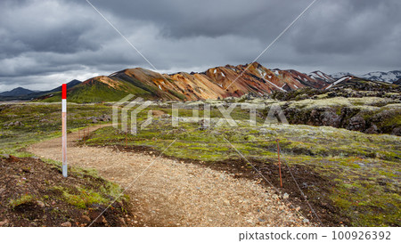 Icelandic landscape of colorful rainbow volcanic Landmannalaugar mountains, at Laugavegur hiking trail with dramatic sky, colorful rhyolite volcano soil and mossed lava fields in Iceland. Icelandic landscape of colorful rainbow volcanic Landmannalaugar mountains, at Laugavegur hiking trail with dramatic sky, colorful rhyolite volcano soil and mossed lava fields in Iceland. 100926392