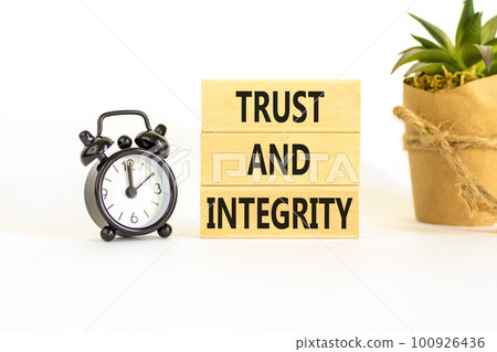 Trust and integrity symbol. Concept words Trust and integrity on wooden blocks. Black alarm clock. Beautiful white background. Business, psychological and trust and integrity concept. Copy space. 100926436