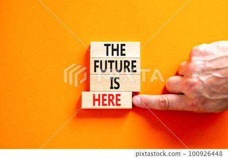 The future is here symbol. Concept words The future is here on wooden block. Beautiful orange table orange background. Businessman hand. Motivational business the future is here concept. Copy space. The future is here symbol. Concept words The future is here on wooden block. Beautiful orange table orange background. Businessman hand. Motivational business the future is here concept. Copy space. 100926448
