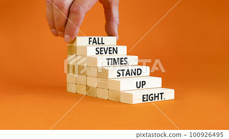 Stand up symbol. Concept words Fall seven times stand up eight on wooden blocks. Beautiful orange table orange background. Businessman hand. Business stand up concept. Copy space. 100926495