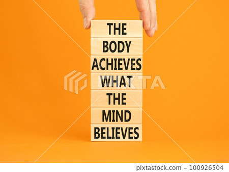 Mind and body symbol. Concept words The body achieves what the mind believes on wooden blocks. Beautiful orange background. Copy space. Businessman hand. Motivational mind and body concept. Mind and body symbol. Concept words The body achieves what the mind believes on wooden blocks. Beautiful orange background. Copy space. Businessman hand. Motivational mind and body concept. 100926504