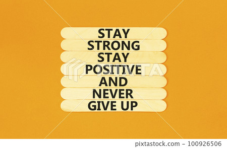 Never give up symbol. Concept words Stay strong stay positive never give up on wooden stick. Beautiful orange table orange background. Copy space. Motivational business never give up concept. 100926506