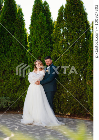the bride and groom hugging and dancing in the park.  100927802
