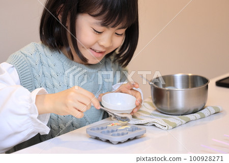 Elementary school girl (8 years old) making white chocolate Elementary school girl (8 years old) making white chocolate 100928271