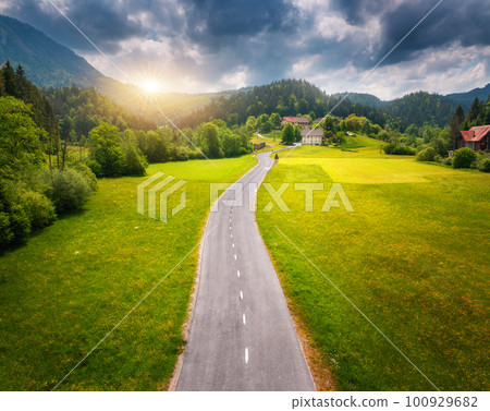 Aerial view of road in green meadows and hils at sunset in summer 100929682