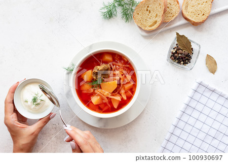 woman eating red borscht with vegetables, meat and sour cream. Traditional slavic dish with beetroot, cabbage, tomato. top view. White background. copy space 100930697