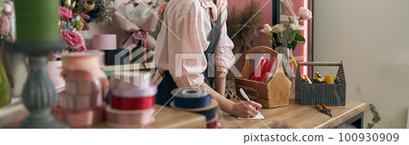 Professional florist young woman is doing bouquets at flower shop 100930909