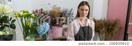 Professional florist young woman is doing bouquets at flower shop 100930910