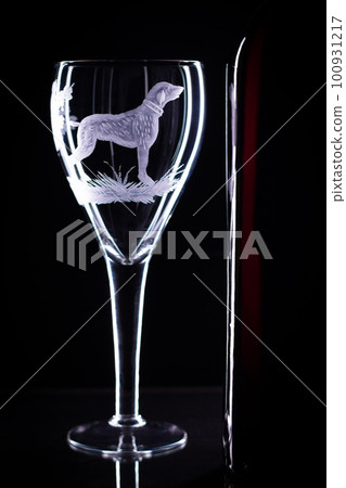 Wine glass with a sandblasted dog and a bottle of wine on a black background. Copy space Wine glass with a sandblasted dog and a bottle of wine on a black background. Copy space 100931217