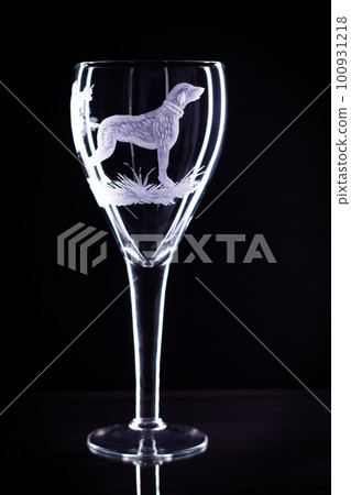 Wine glass with a sandblasted dog on a black background. Copy space 100931218