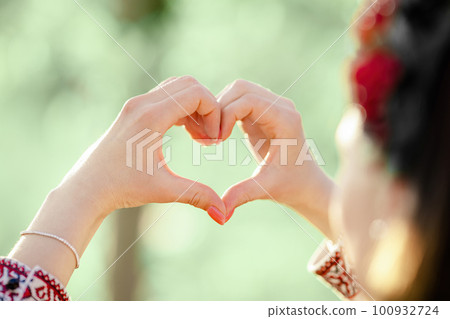 Woman in traditional embroidery vyshyvanka dress making sign of shape heart. 100932724