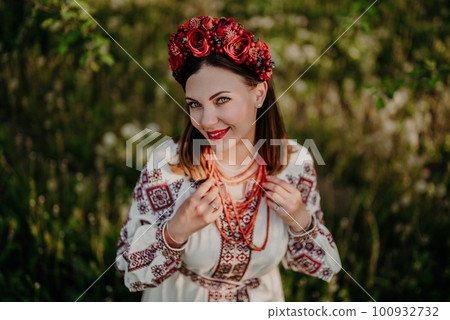 Attractive ukrainian woman in embroidery vyshyvanka,ancient coral beads on grass Attractive ukrainian woman in embroidery vyshyvanka,ancient coral beads on grass 100932732